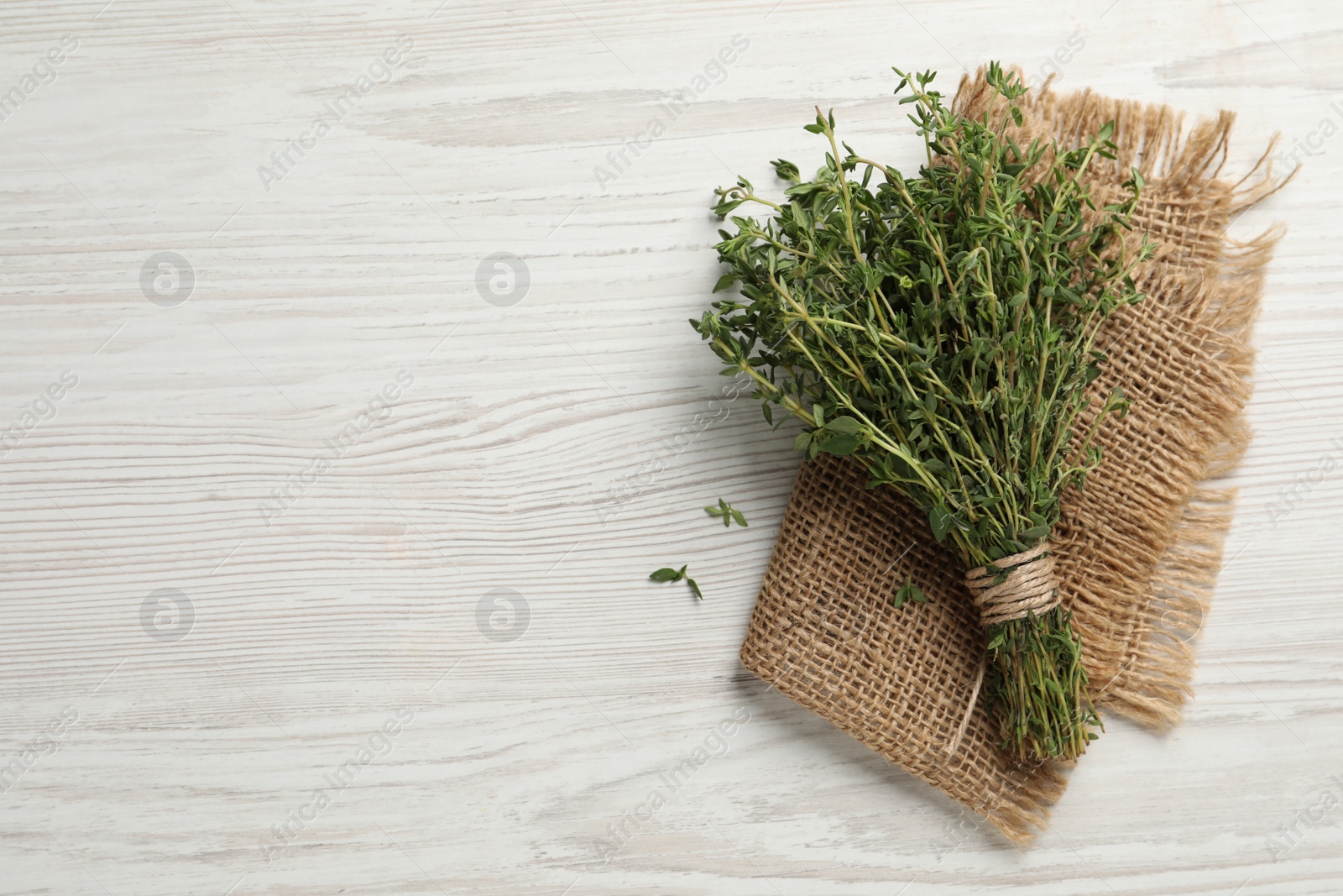 Photo of Bunch of aromatic thyme on white wooden table, top view. Space for text