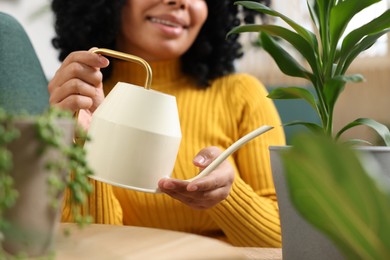 Happy woman watering beautiful potted houseplant at home, closeup