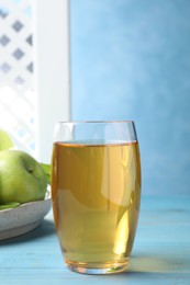 Photo of Glass of fresh apple juice on light blue wooden table
