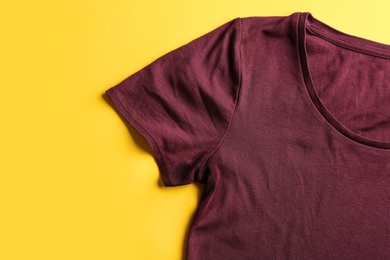 Photo of T-shirt with deodorant stain on yellow background, top view