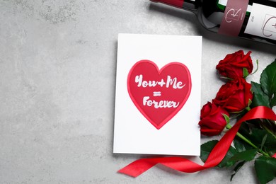 Marvelous message of love with red roses and wine on grey table, flat lay. Space for text