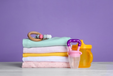 Photo of Children's accessories and stack of clothes on white wooden table