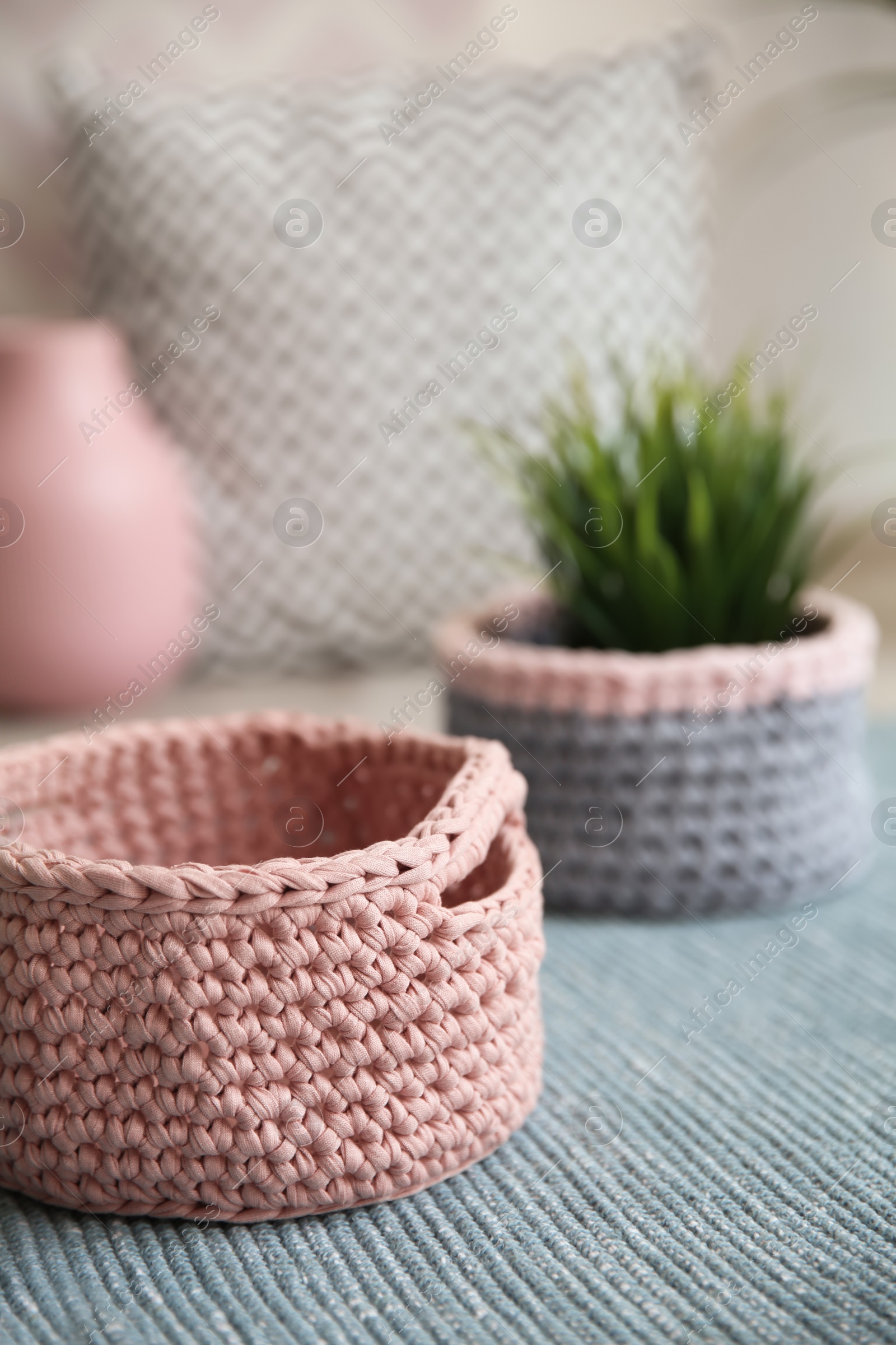 Photo of Empty knitted flowerpot cover on carpet. Interior element