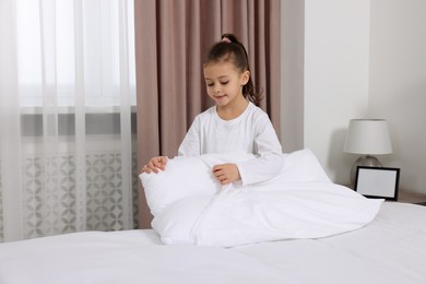 Photo of Cute girl changing pillowcase in bedroom. Domestic chores