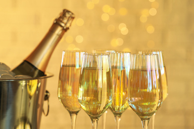 Glasses of champagne and ice bucket with bottle on blurred background