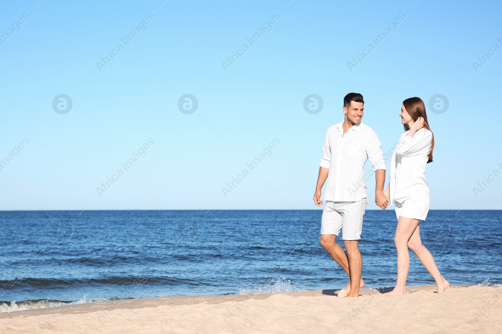 Photo of Lovely couple walking on beach. Space for text