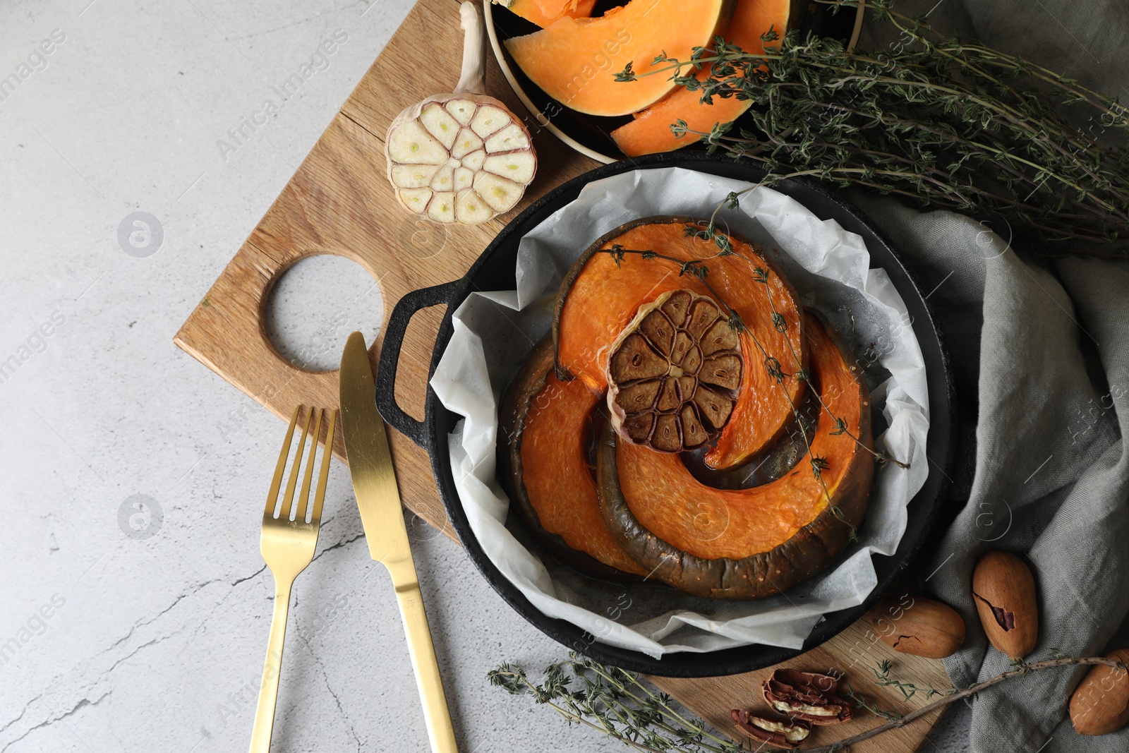 Photo of Freshly baked pumpkin slices with garlic and thyme on light table, flat lay