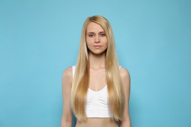 Photo of Beautiful young woman with long straight hair on light blue background