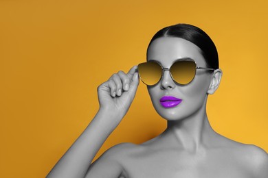 Image of Attractive woman in stylish sunglasses on orange background. Color accent