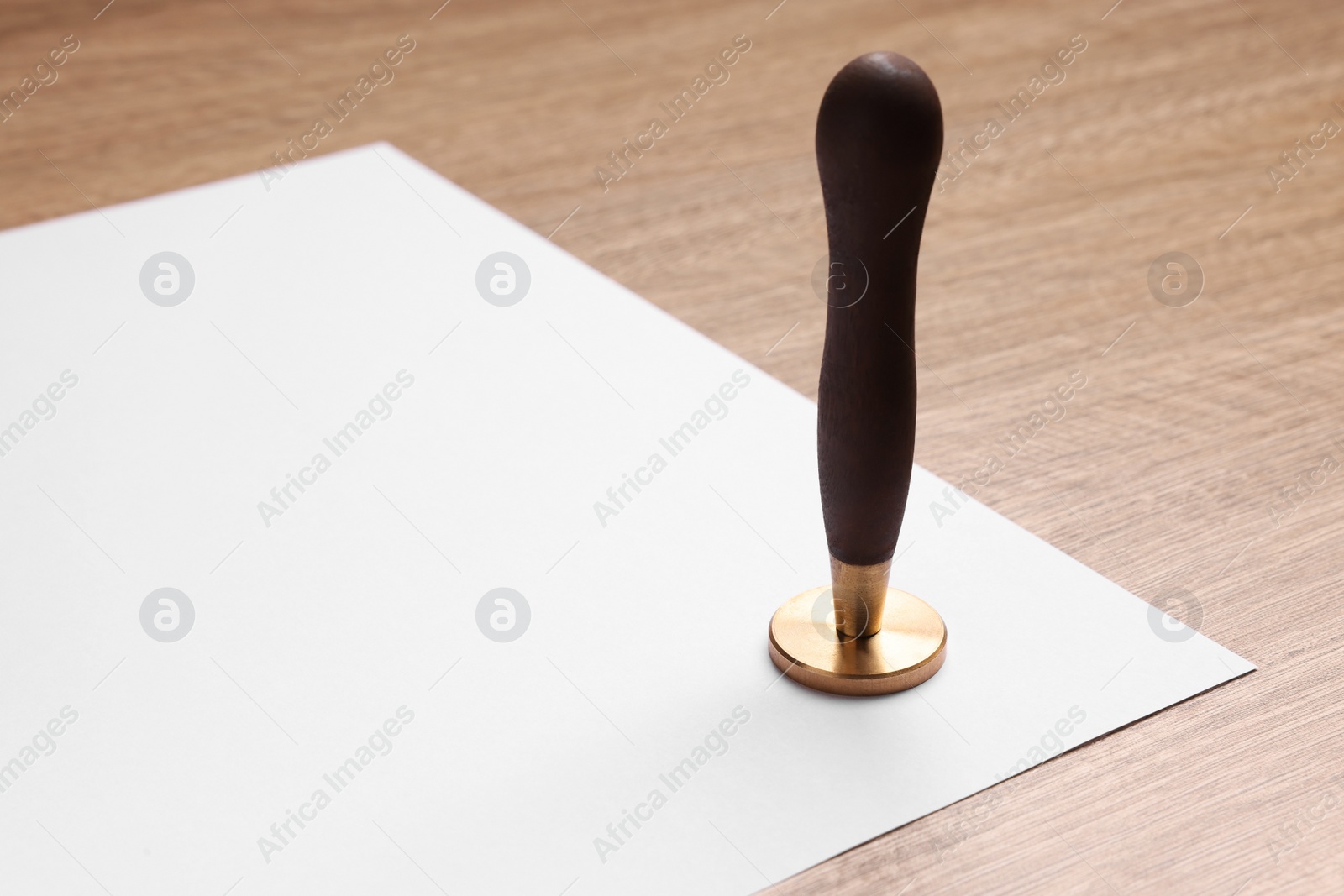 Photo of One stamp tool and sheet of paper on wooden table. Space for text