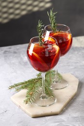 Photo of Christmas Sangria cocktail in glasses and fir tree branch on grey textured table