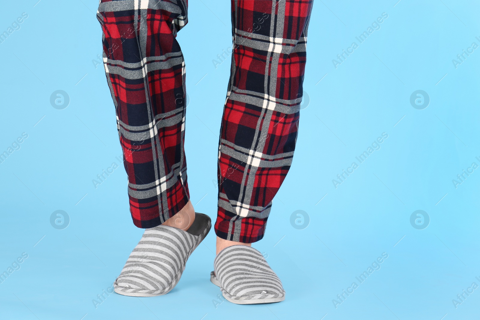 Photo of Man in warm soft slippers on light blue background, closeup