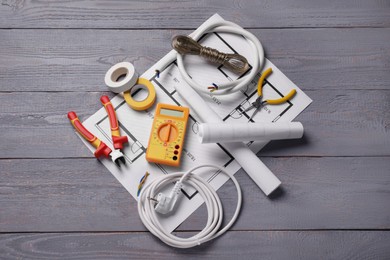 Different wires, electrician's tools and schemes on wooden table, flat lay