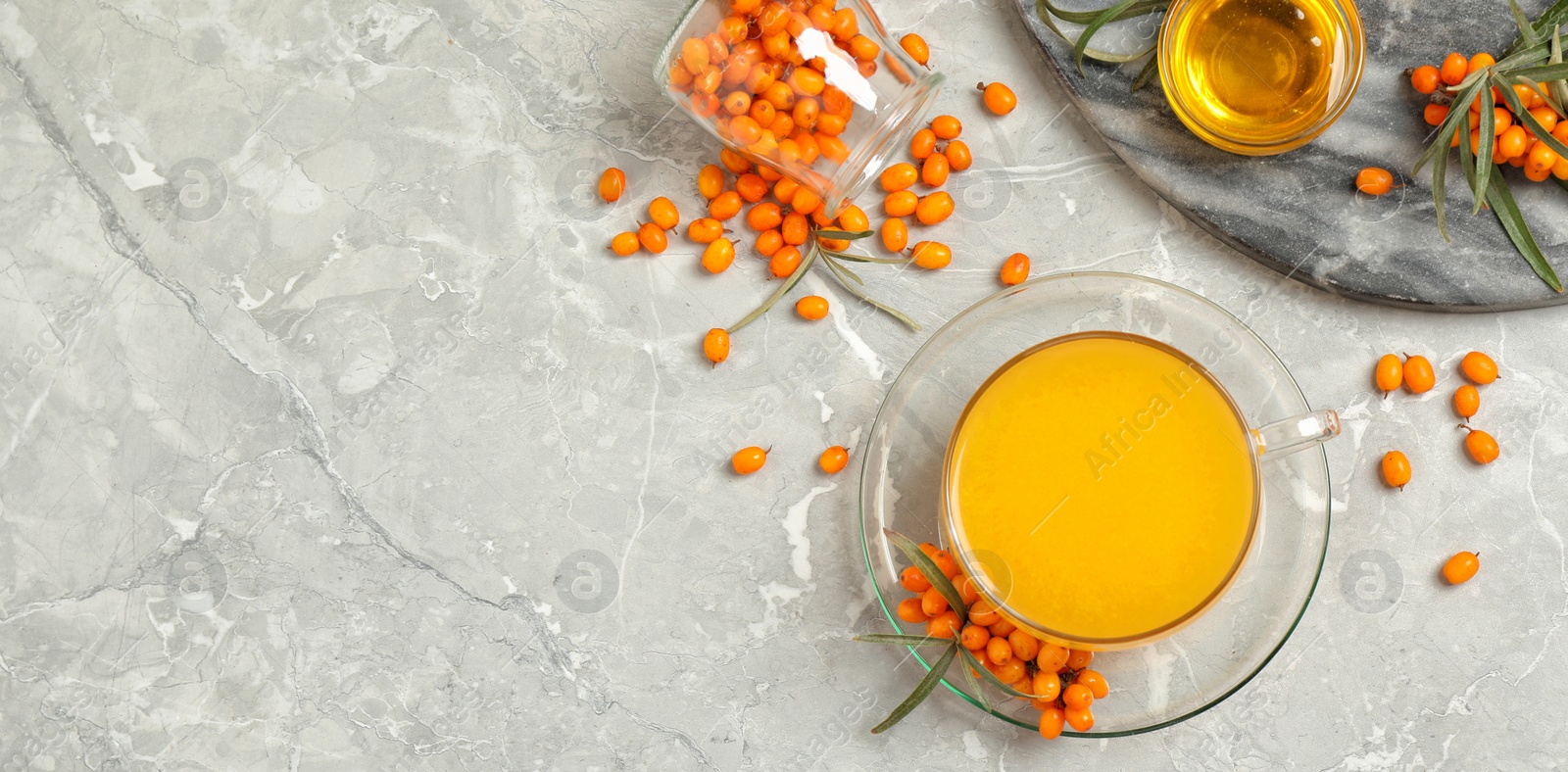 Image of Delicious sea buckthorn tea and fresh berries on grey marble table, flat lay. Banner design with space for text