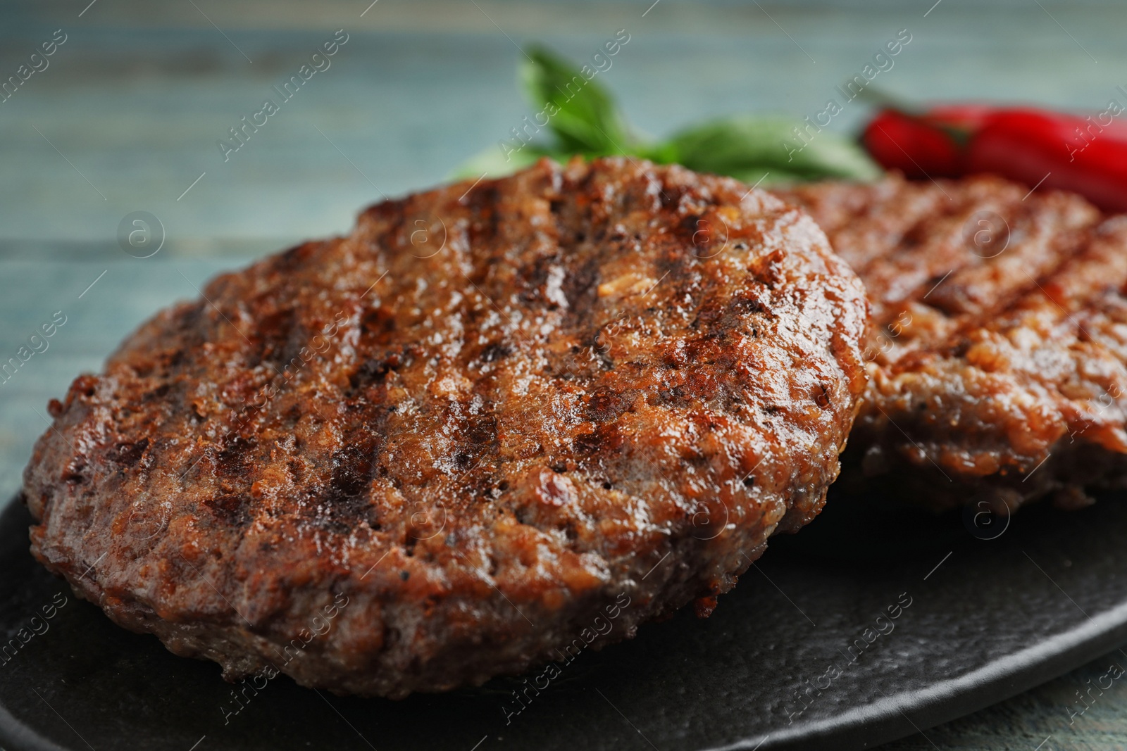 Photo of Grilled meat cutlets for burger on blue wooden table, closeup