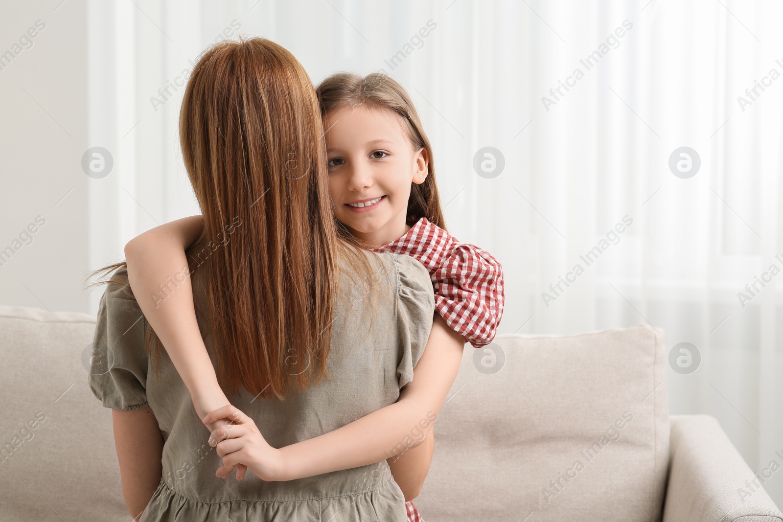 Photo of Cute daughter hugging her mom at home. Space for text