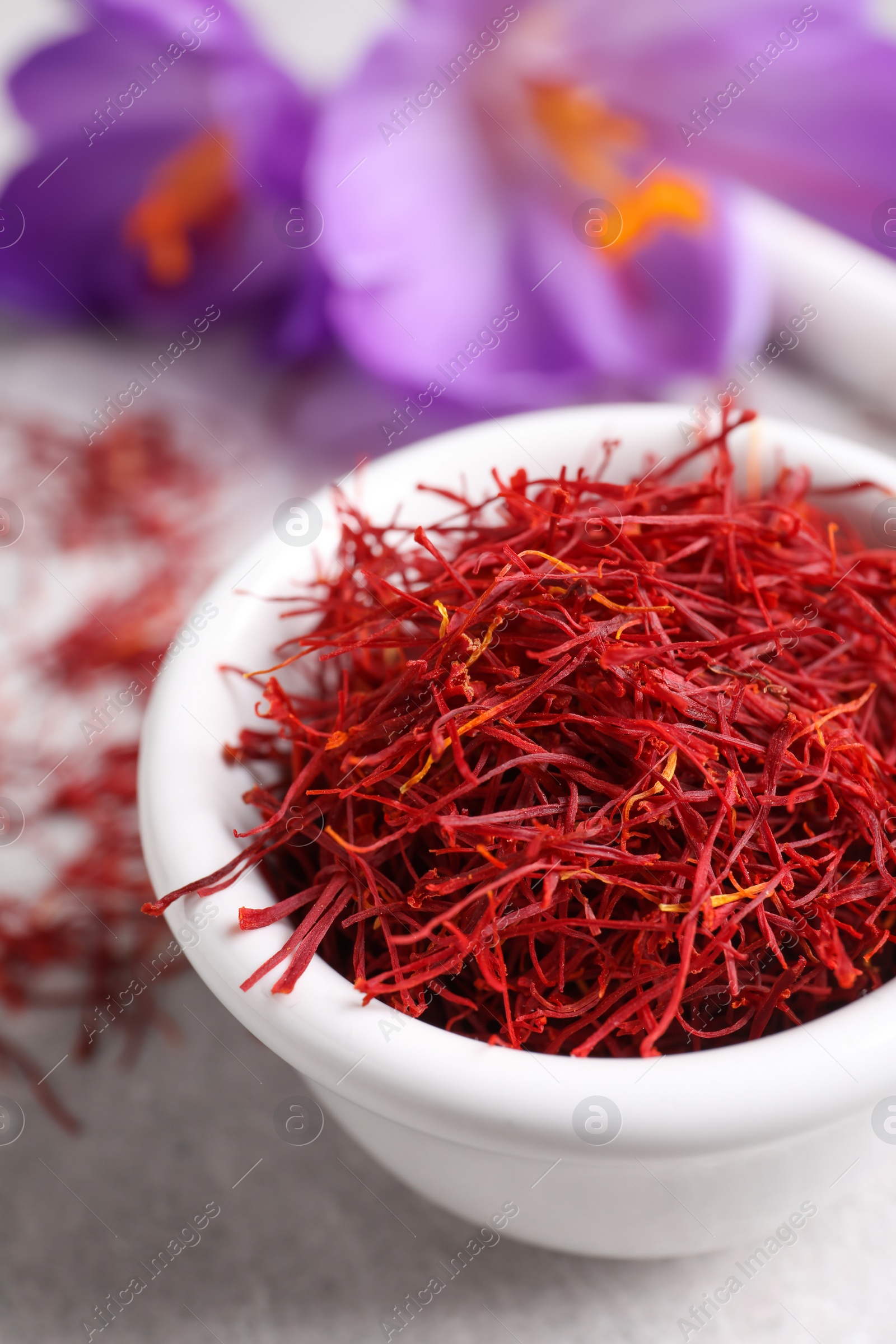 Photo of Dried saffron and crocus flowers on grey table, closeup