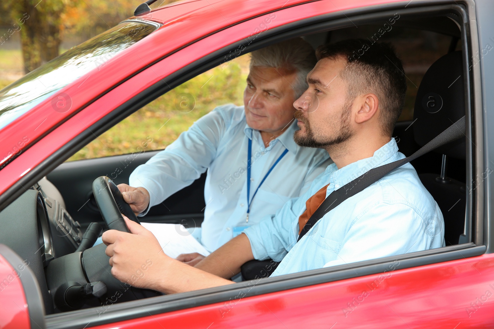 Photo of Man and instructor in car. Passing driving license exam