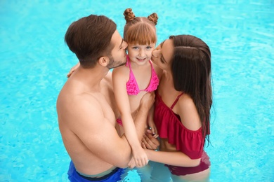 Photo of Parents kissing their daughter in swimming pool