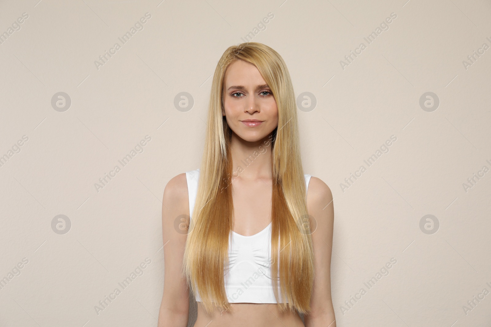 Photo of Beautiful young woman with long straight hair on beige background
