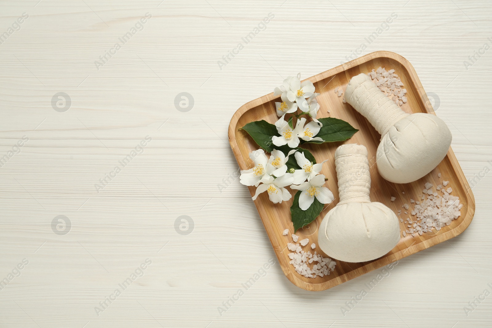 Photo of Beautiful jasmine flowers, herbal bags and sea salt on white wooden table, top view. Space for text