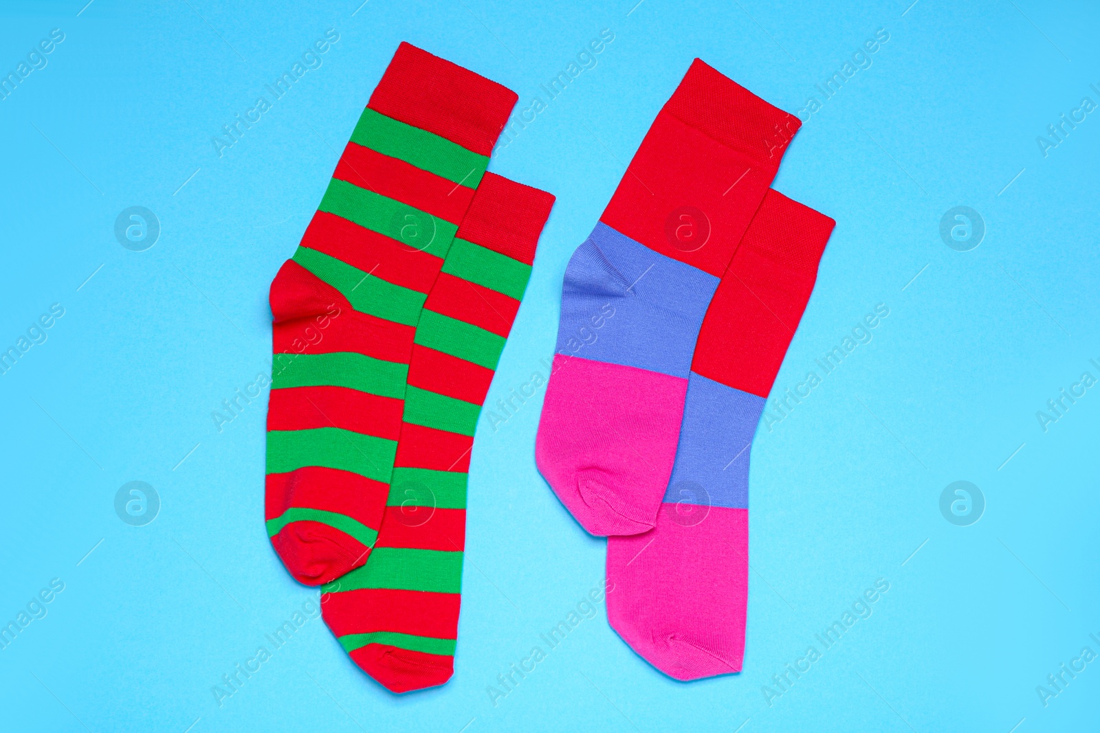 Photo of Different striped socks on light blue background, flat lay