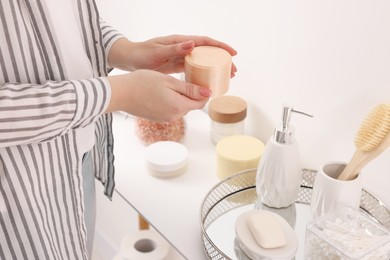 Photo of Bath accessories. Woman with jar of cosmetic product indoors, closeup