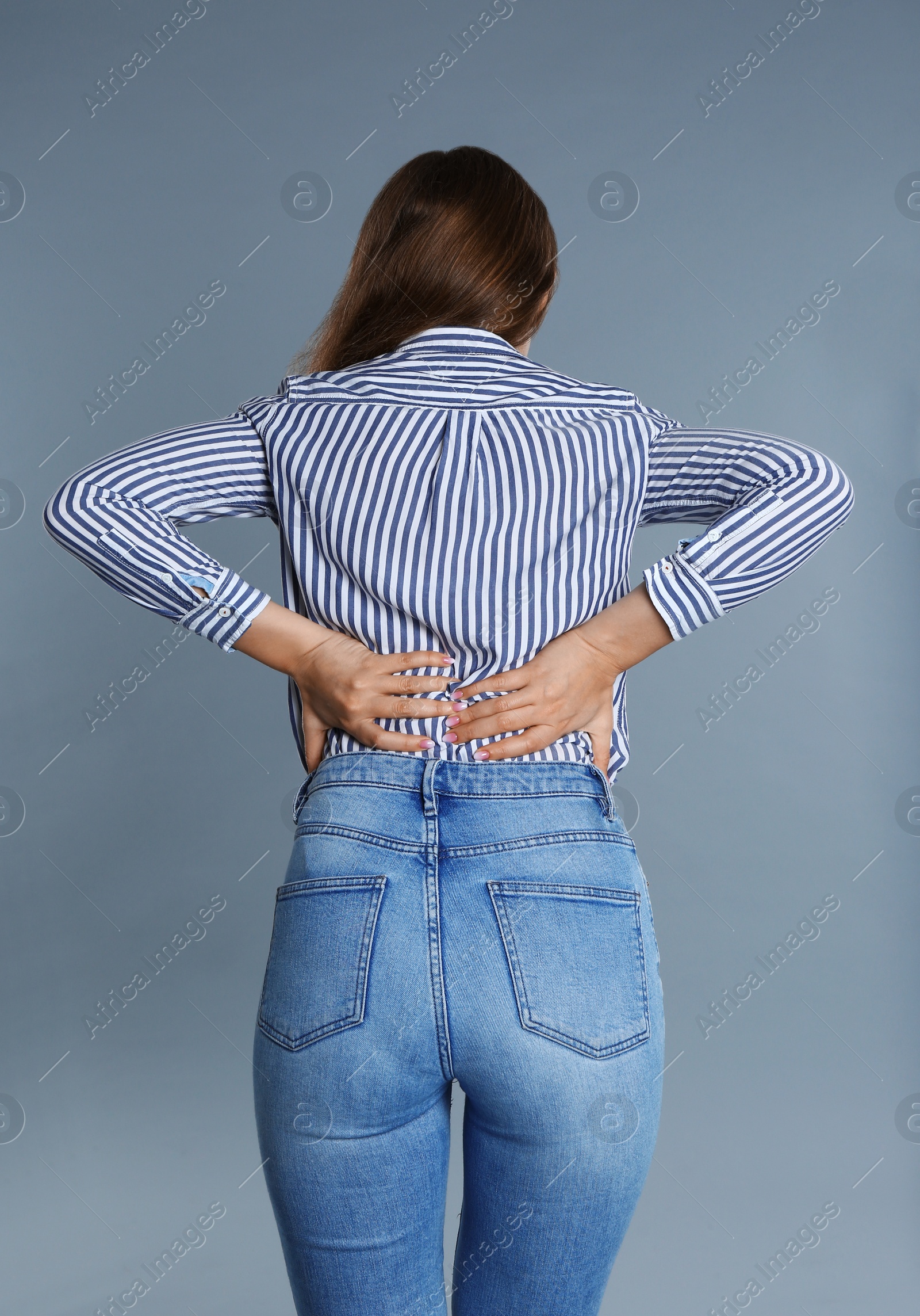 Photo of Woman suffering from back pain on grey background