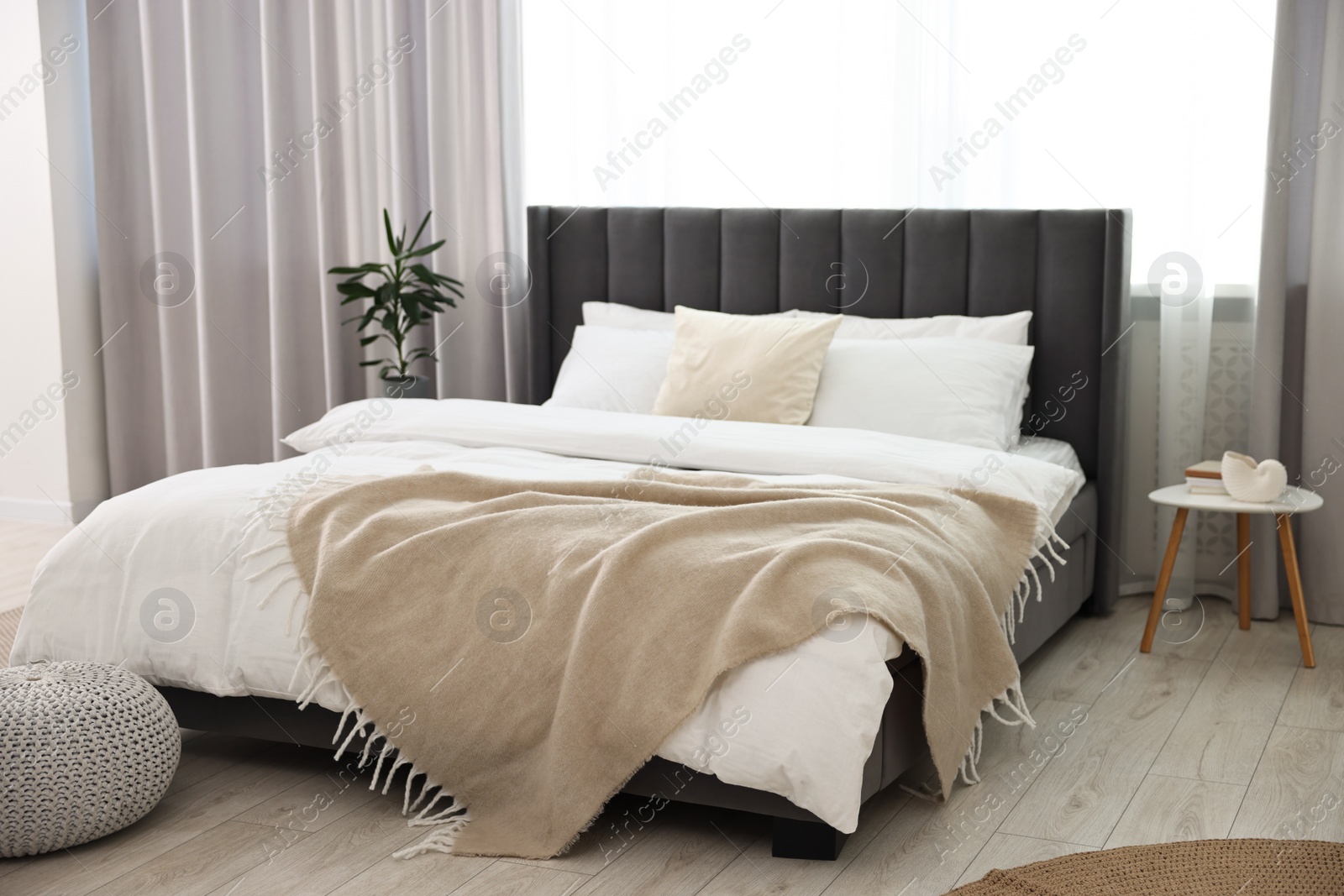 Photo of Soft beige plaid on bed in stylish bedroom. Interior design