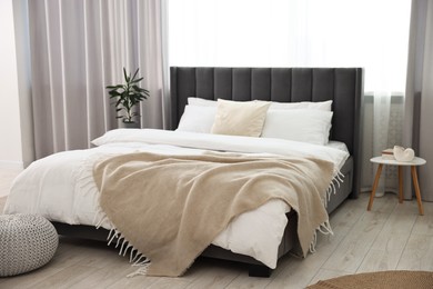 Photo of Soft beige plaid on bed in stylish bedroom. Interior design