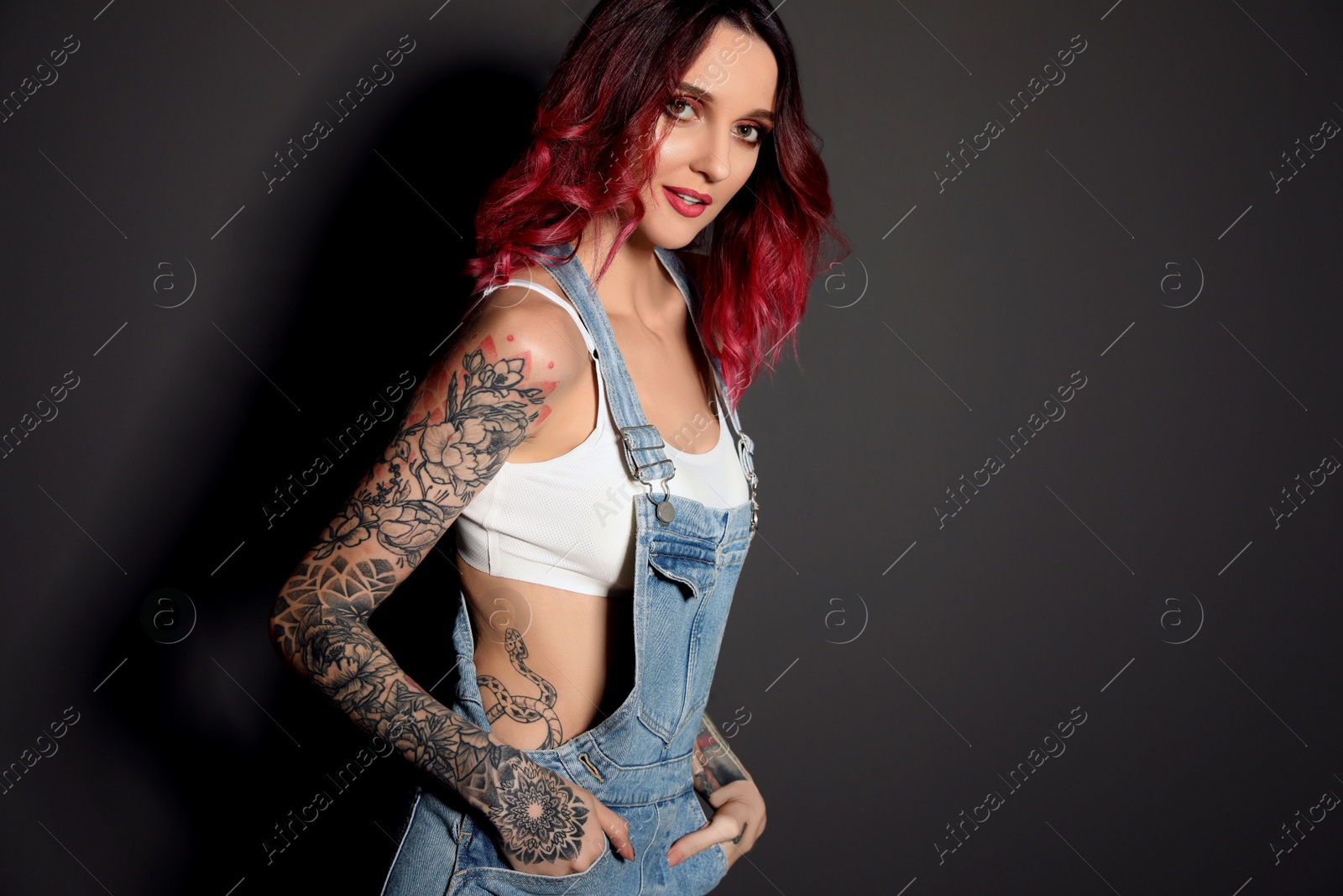 Photo of Beautiful woman with tattoos on body against black background. Space for text