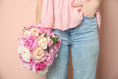 Woman with bouquet of beautiful peonies on beige background, closeup