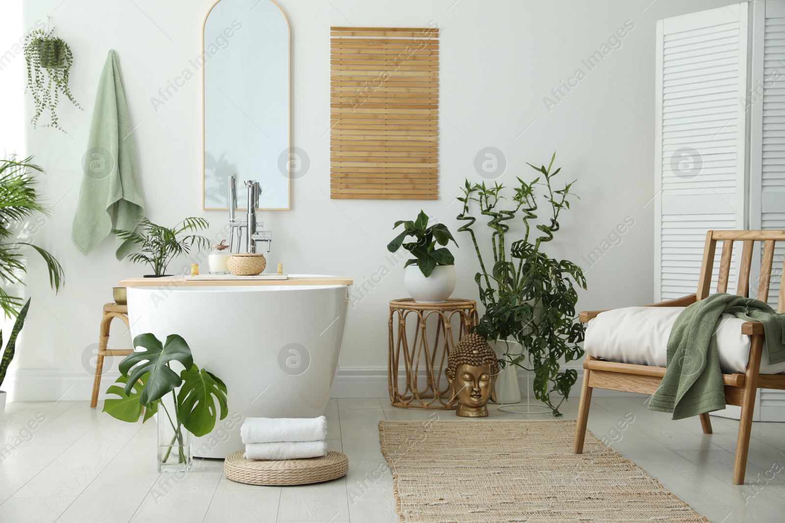 Photo of Stylish bathroom interior with modern tub, houseplants and beautiful decor. Home design