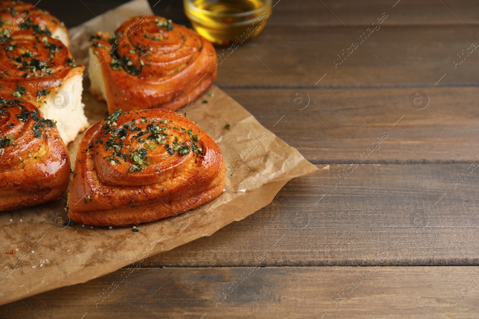 Photo of Traditional Ukrainian bread (Pampushky) with garlic on wooden table, space for text