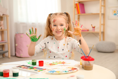 Cute little child painting with palms at table