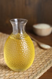 Photo of Fresh sesame oil on wooden table, closeup