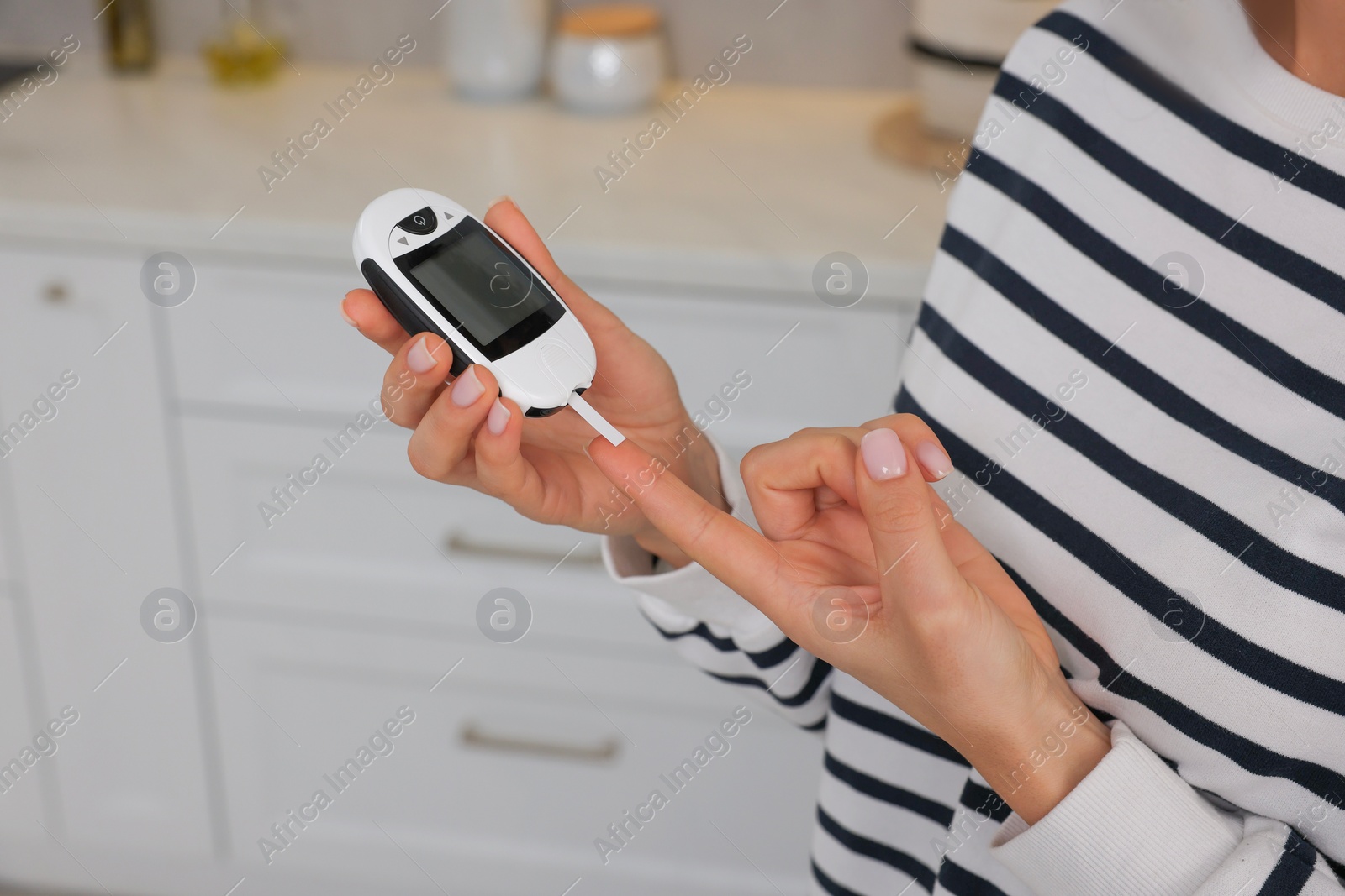 Photo of Diabetes. Woman checking blood sugar level with glucometer in kitchen, closeup
