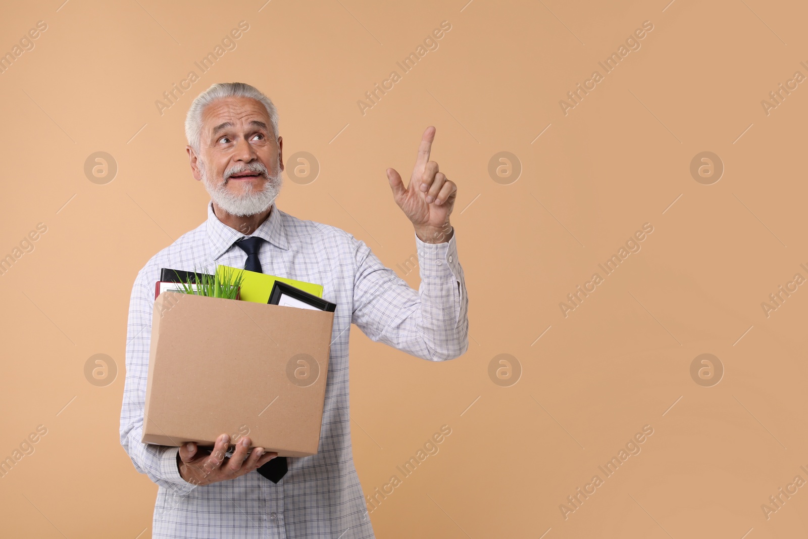 Photo of Happy unemployed senior man with box of personal office belongings on beige background. Space for text