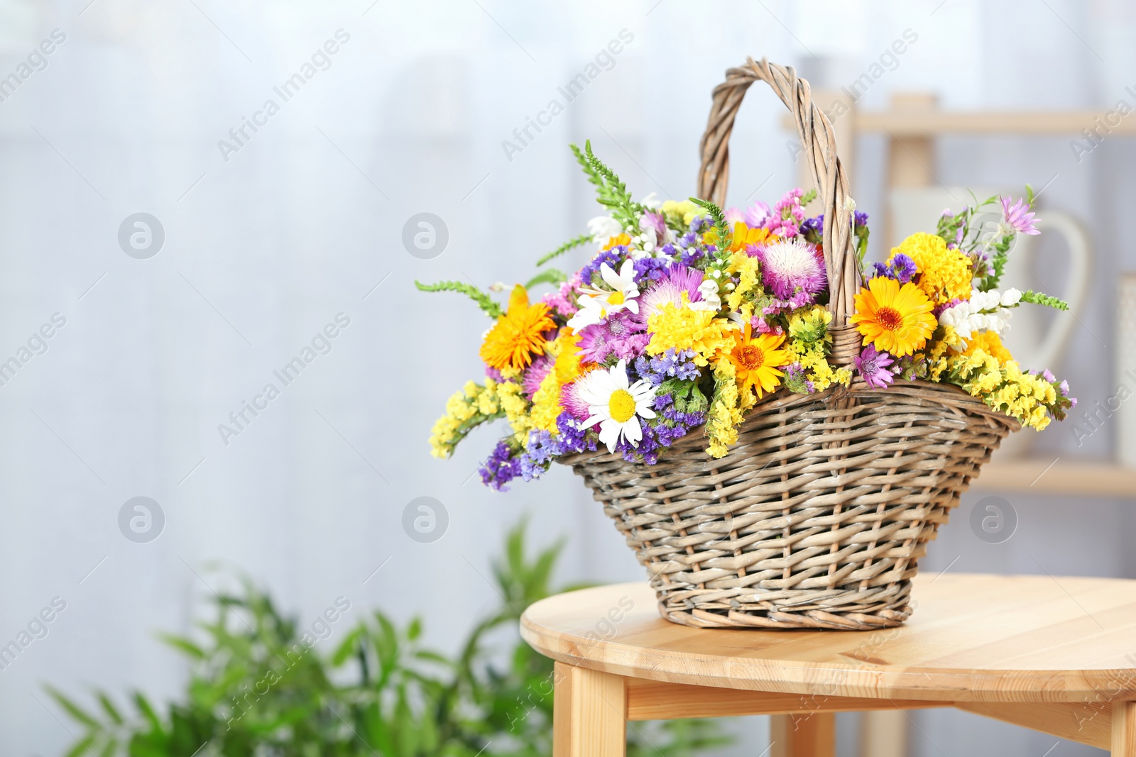 Photo of Wicker basket with beautiful wild flowers on table indoors