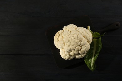 Fresh raw cauliflower on black wooden table, top view. Space for text