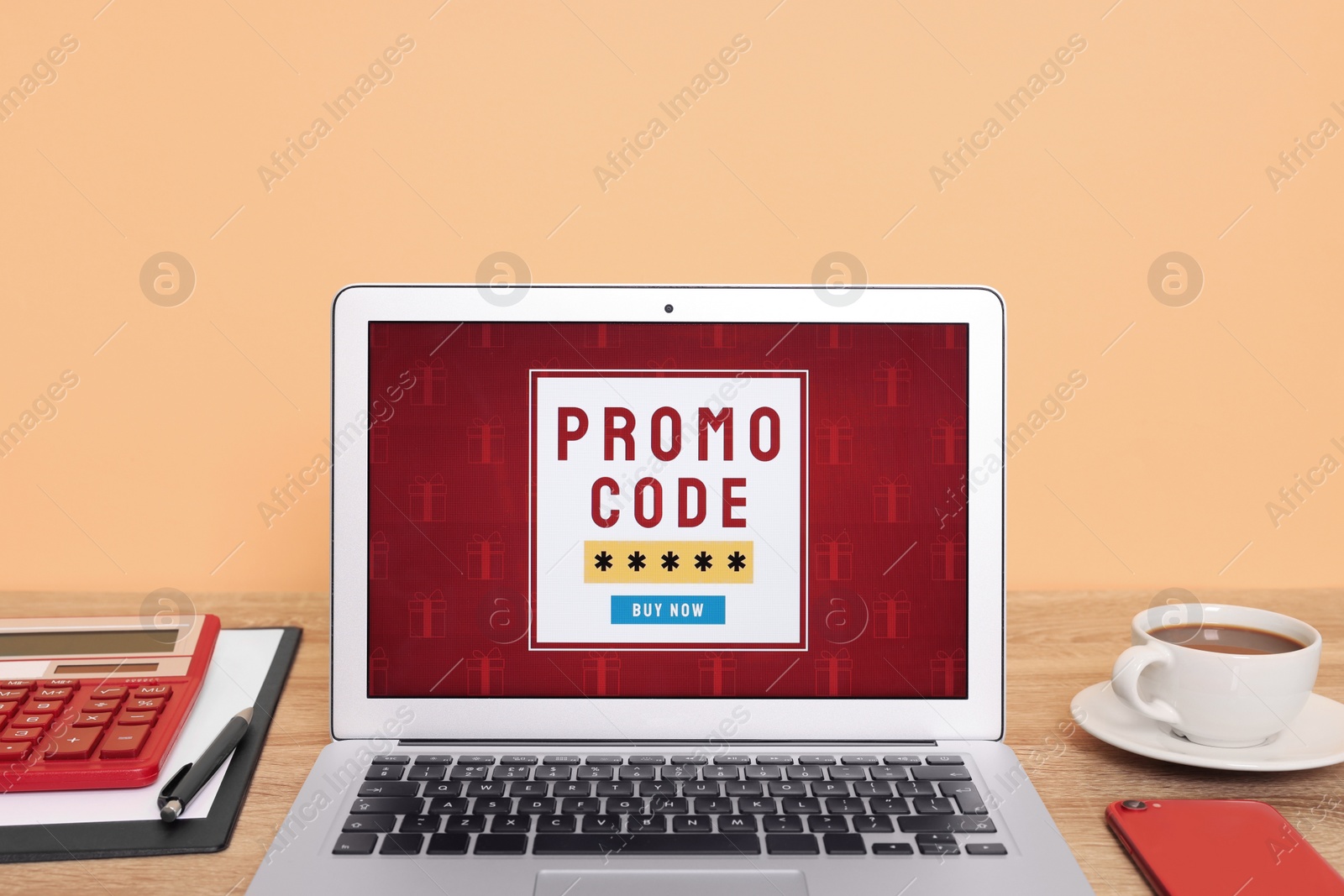 Photo of Laptop with activated promo code on wooden table near beige wall