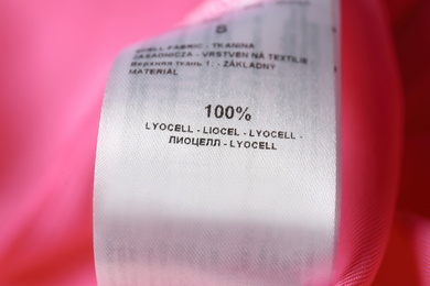 Photo of Clothing label with material content on pink shirt, closeup view