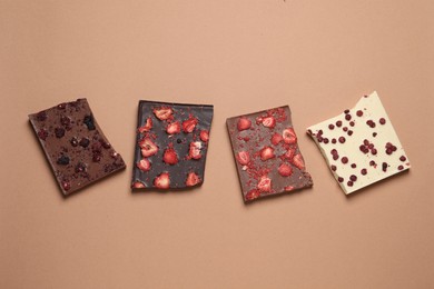 Different chocolate bars with freeze dried fruits on beige background, flat lay