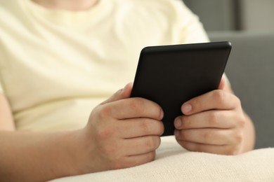 Photo of Man using e-book reader indoors, closeup view