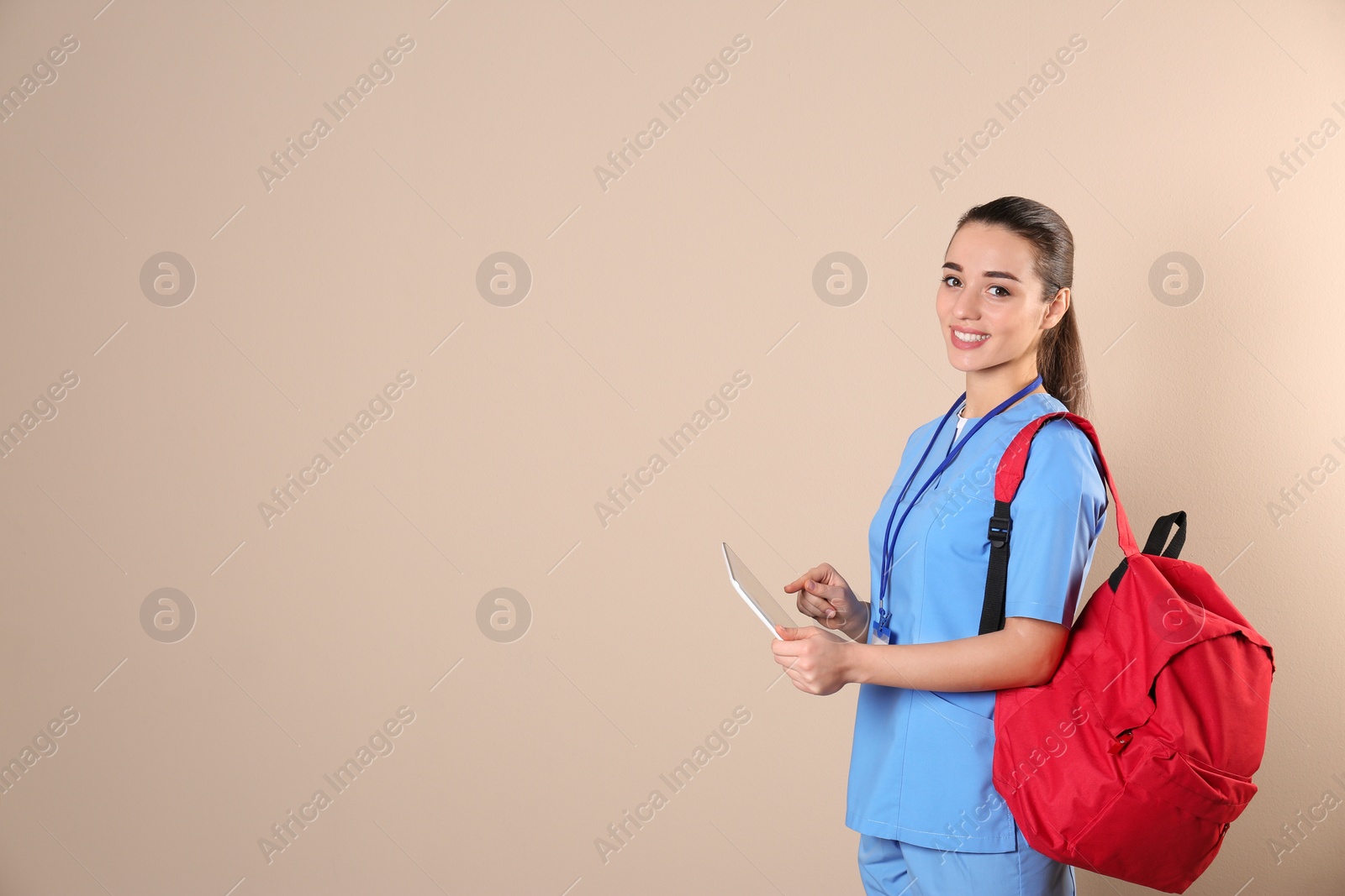 Photo of Young medical student with tablet and backpack on color background. Space for text