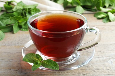 Cup of hot aromatic tea with mint on wooden table, closeup