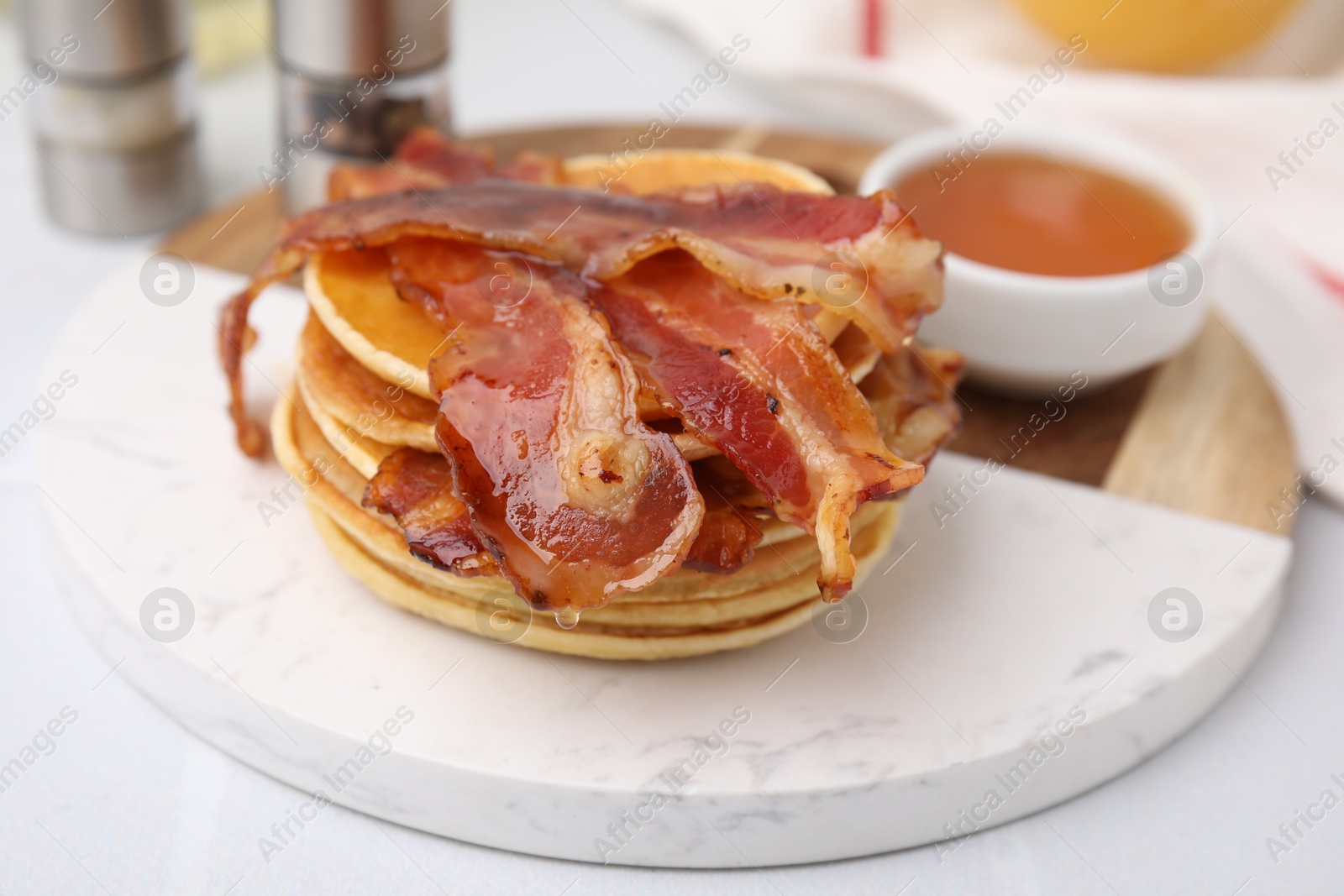 Photo of Delicious pancakes with bacon and honey on white table, closeup