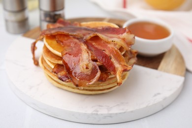 Delicious pancakes with bacon and honey on white table, closeup