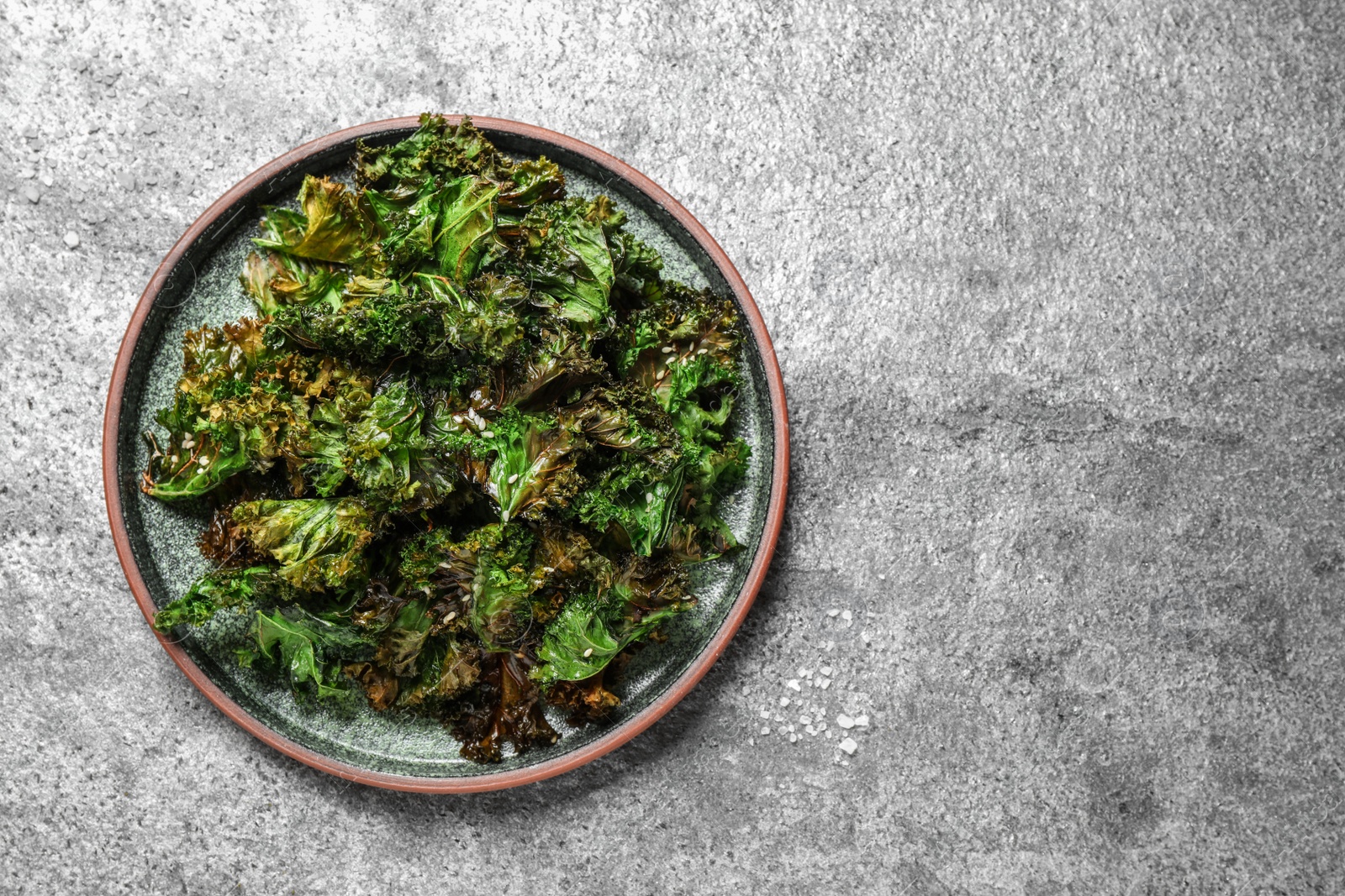 Photo of Tasty baked kale chips on grey table, top view. Space for text