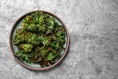 Photo of Tasty baked kale chips on grey table, top view. Space for text